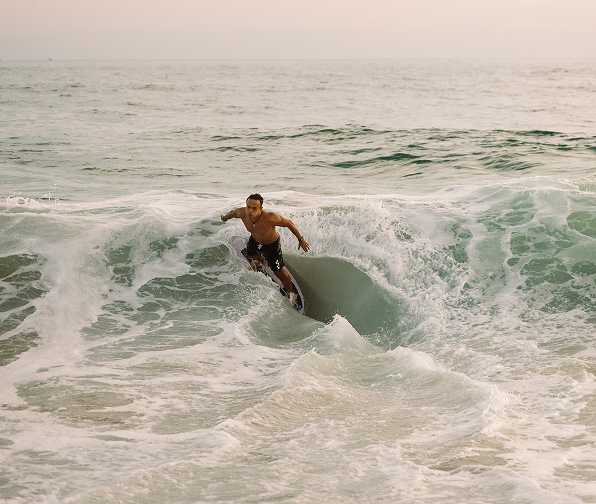 A clear scene of a man surfing wild waves with a sunset