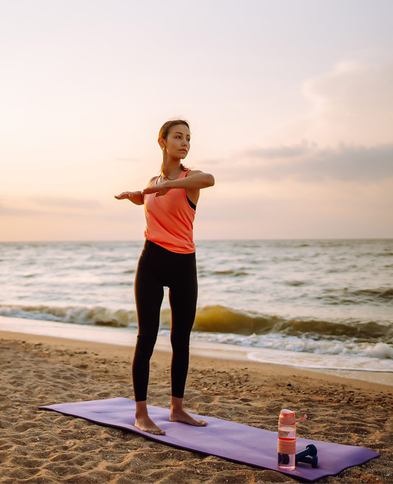 Outdoor yoga class facing the sea at sunrise at the hotel